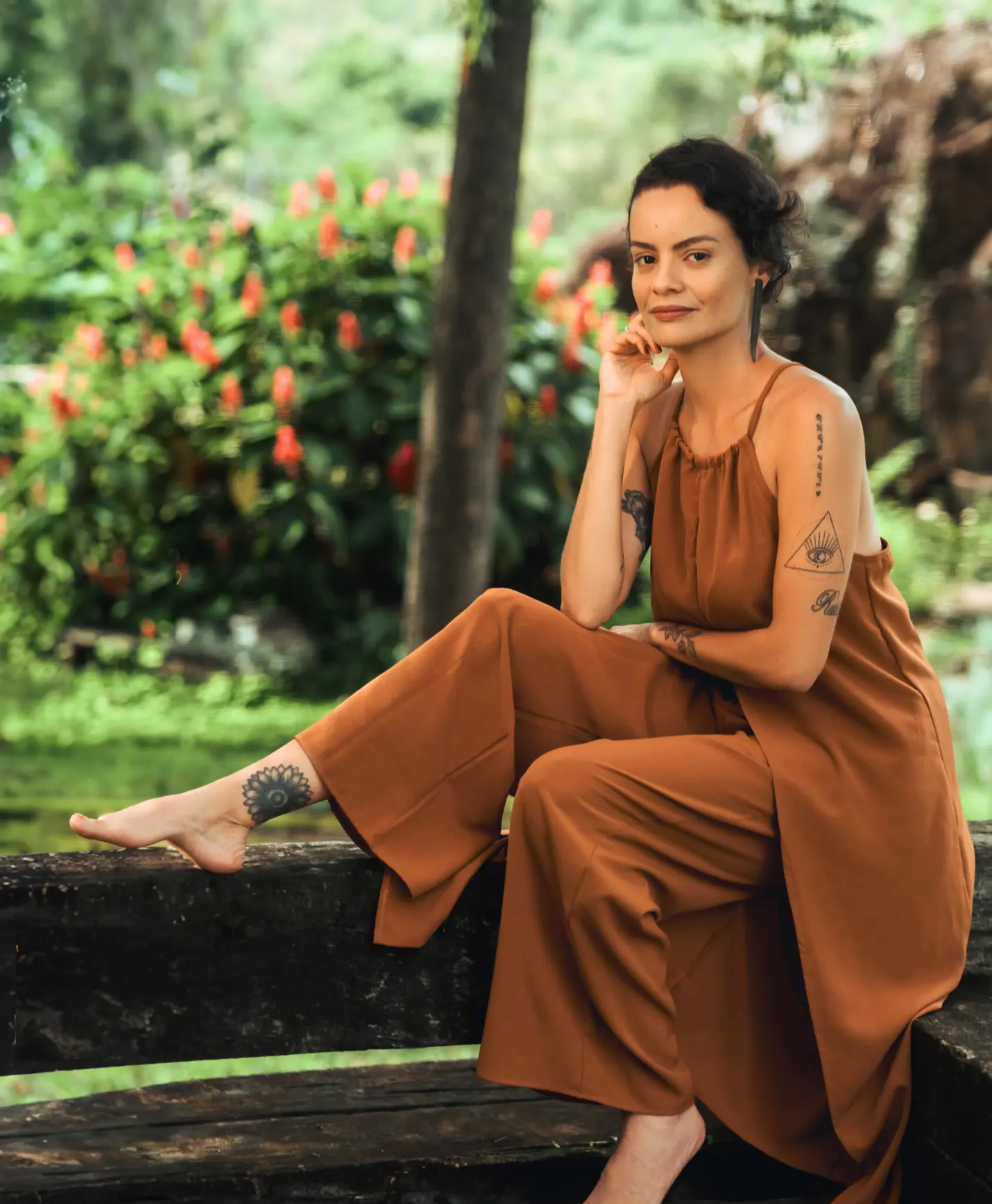 Kariny Elias sentada em uma ponte de madeira, cercada por vegetação